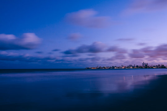 Landscape photo of an urban beach after sunset with purple sky and sea