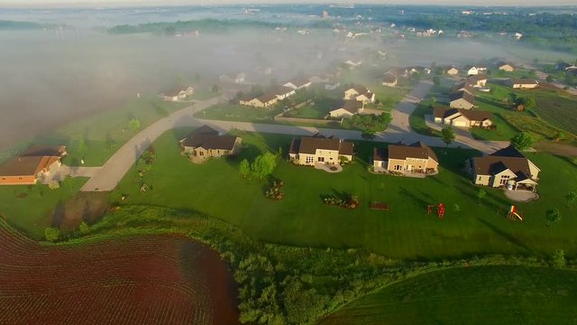 Beautiful neighborhoods, homes, suburbs, under spectacular foggy sunrise, aerial view.
