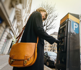Woman paying for the parking at the teller machine in the city