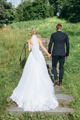 bride and groom holding hands going up outdoors