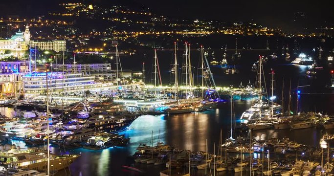 Timelapse of World Fair MYS Monaco Yacht Show at night, Port Hercules, luxury megayachts, many shuttles, party time, boat traffic, long exposure, aerial view, cityscape, night lights, illumination