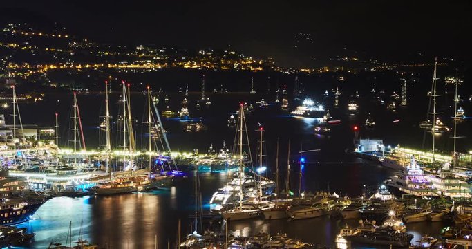 Timelapse of World Fair MYS Monaco Yacht Show at night, Port Hercules, luxury megayachts, many shuttles, party time, boat traffic, long exposure, aerial view, cityscape, night lights, illumination