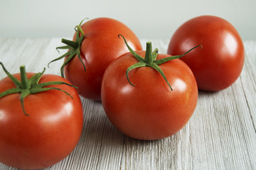four red tomatoes scattered on wood table