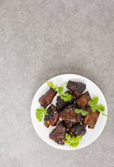 Chinese sweet and sour ribs. on a white plate. Dark gray stone background. Copy space. 
