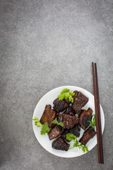 Chinese sweet and sour ribs. on a white plate. Dark gray stone background. Copy space. 