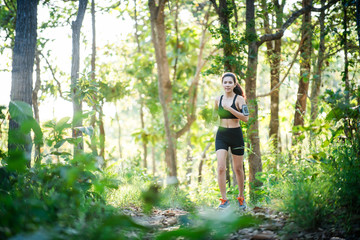 Fototapeta na wymiar Young woman jogging on rural road in green forest nature.