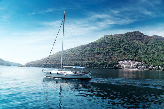 Sailing yacht swimming at blue sea near forest mountains
