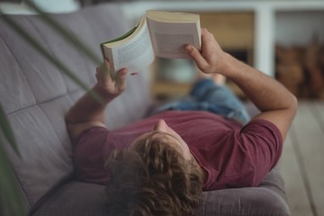 Man lying on sofa and reading book