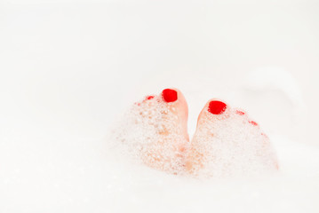 Feet with red nails soaking in spa bath