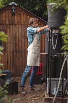 Man pouring sack of barley into wort to make beer