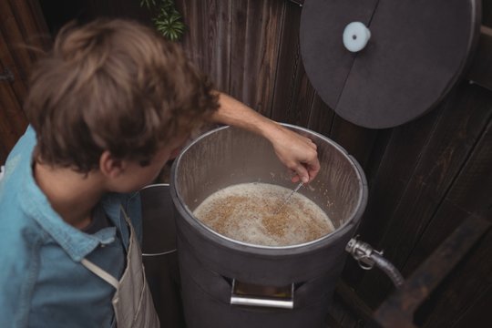 Man Testing Temperature Of Beer In Wort While Making Beer