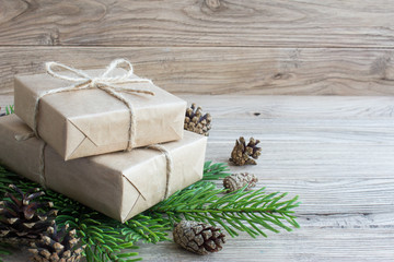 Gift boxes of Kraft paper on Christmas tree with cones. Wooden b