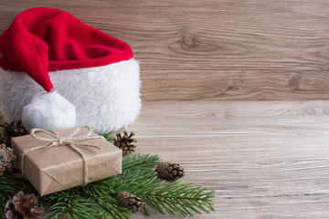 Obraz na płótnie Canvas Gift boxes and Santa hat on Christmas tree. Wood background.