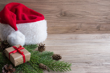 Obraz na płótnie Canvas Gift boxes and Santa hat on Christmas tree. Wood background.