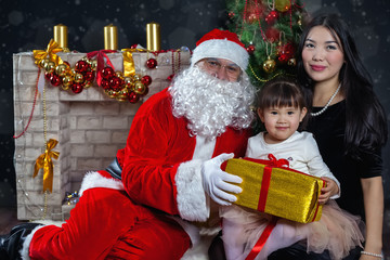 Fototapeta na wymiar Santa Claus and mother with your child in a dress. Christmas Scenes.