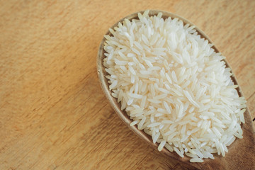 Thai jasmine rice on wooden spoon and wood background vintage and grain picture style
