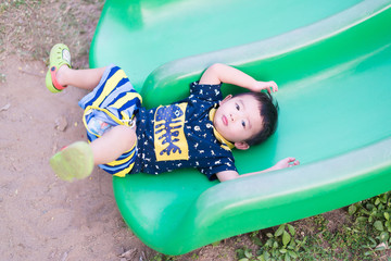 Fototapeta premium Little Asian kid playing slide at the playground.