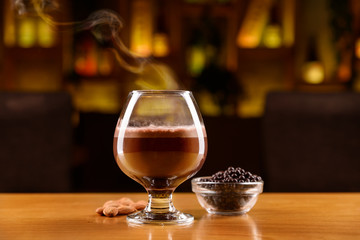 Cocktail with alcohol, coffee, cocoa and chocolate on a layers. Almonds and chocolate balls on a wooden table.