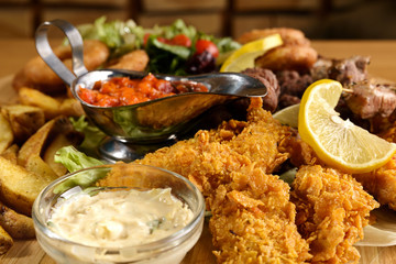 Meat combo dish with green salad, fries, onion rings and sauces