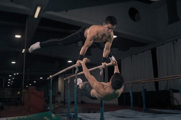 Obraz na płótnie Canvas Two men gymnast in air, parallel bars