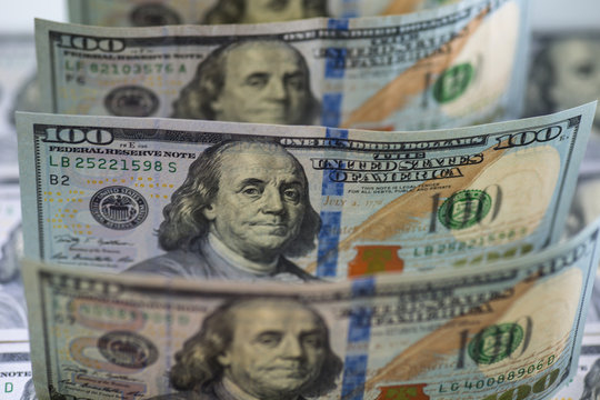 Row of hundred us dollar bills. Backlight, watermarks are visible. Selective focus. Bills are standing on hundred us banknotes background. Close up image.
