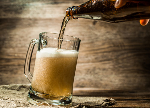 Foamy beer from bottle poured into mug