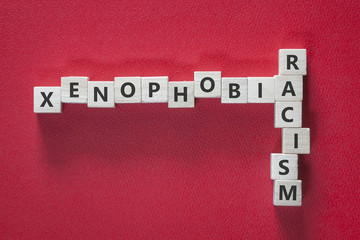 Xenophobia and racism words written with blocks on red background. Social issues concept