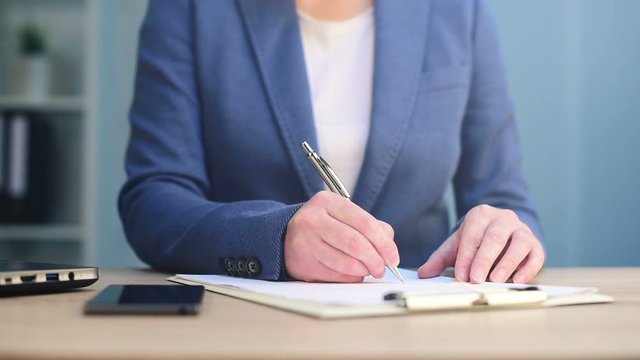 Businesswoman signing business contract agreement at office desk