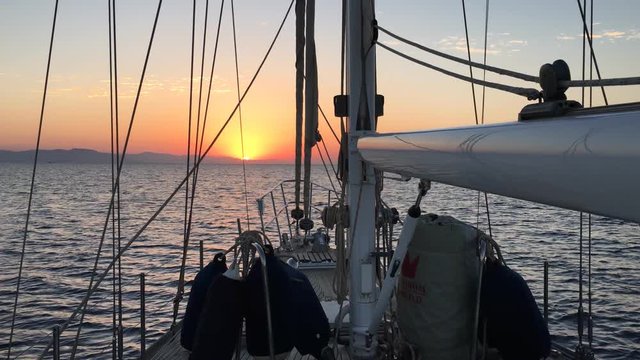 Sailboat Approaching Land at Sunrise in the Sea
