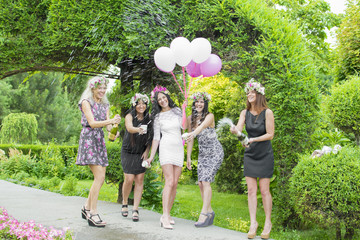 Three young and beautiful girl celebrating and champagne splash. The colorful summer park.