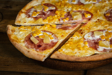 Pizza with corn, ham and pineapple on wood background 