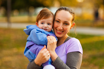 Portrait of mother and baby boy in the park in the autumn. Looki