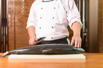 Japanese Chef preparing a fresh salmon on a cutting board 
