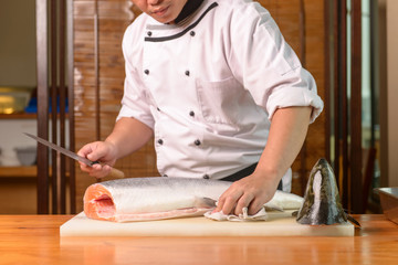 Japanese Chef preparing a fresh salmon on a cutting board 
