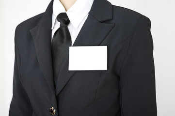 White blank name tag id business card template is attached to chest of a businessman in a black suit. Businesswoman wear blank white badge mockup, stand isolated