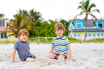 Two kid boys building sand castle on tropical beach