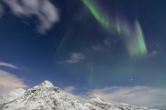 Northern lights (Aurora Borealis) and stars light up the snowy peaks, Vareid, Flakstad, Nordland, Lofoten Islands, Northern Norway