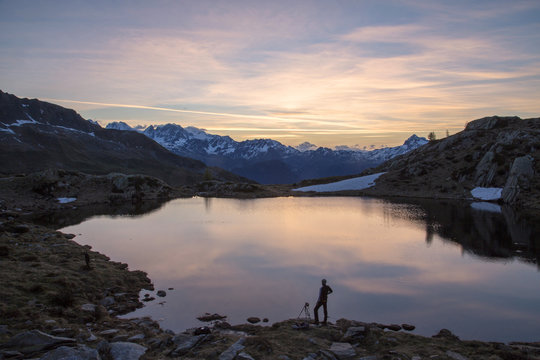 Photographer admires the pink sunrise on Lake Zana, Malenco Valley, Valtellina, Province of Sondrio, Lombardy