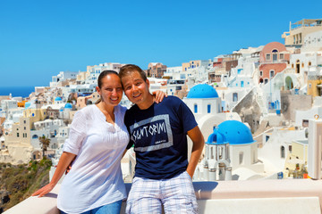 Portrait of happy couple with cityscape of Oia, Santorini on bac