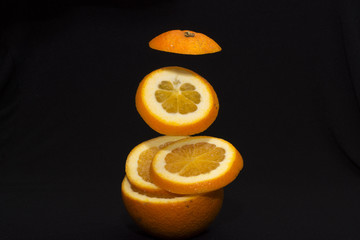 Levitating fresh sliced fruit, orange isolated on black background. Healthy food.