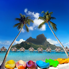bright canoes between palm trees and the mountain Otemanu. Bora-Bora. Tahiti..
