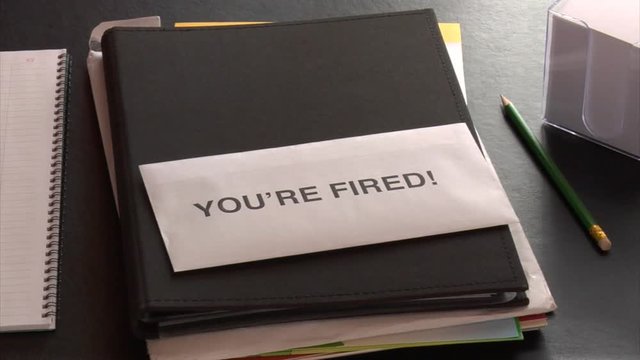 Getting a YOU'RE FIRED notice at office desk with undone paperwork