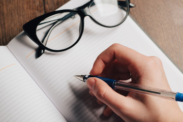 glasses, pen writing in notepad, copy space
