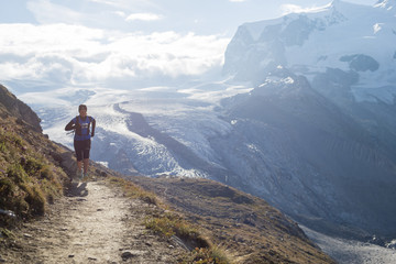 Running a trail in the Swiss Alps near Zermatt with a view of Monte Rosa in the distance, Zermatt, Valais