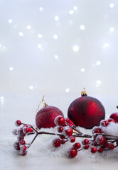 Christmas scene with snow - red balls with berries and lights in background