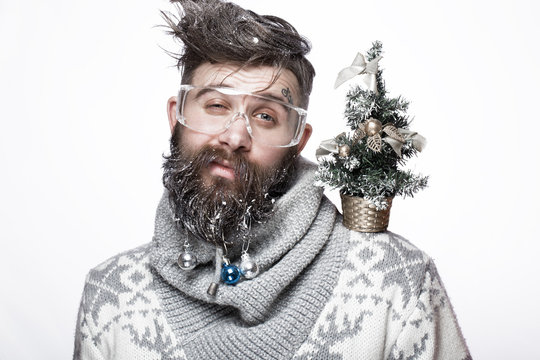 Funny bearded man in a New Year's image with snow and decorations on his beard. Feast of Christmas. Photos shot in the studio.