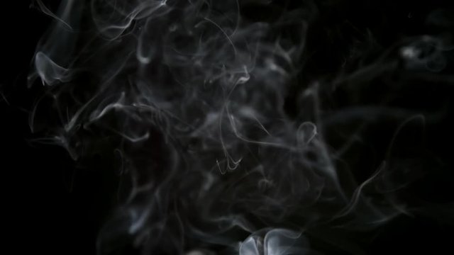 SLOW MOTION: Thin smoke lifts up on a dark background