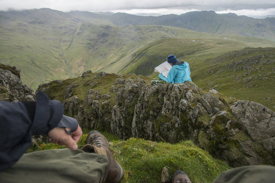 A woman checks her map while looking towards Great Langdale valley from the Langdale Pikes, Lake District National Park, Cumbria