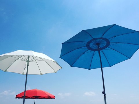 Red, white and blue beach parasols against a blue sky, Nice, Alpes Maritimes, Cote d'Azur, French Riviera, Provence, France