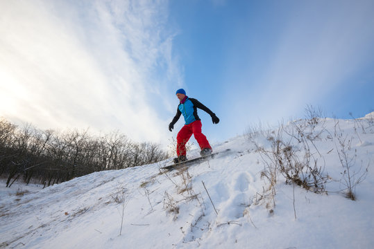 Snowboarder is riding in winter forest. Wide angle